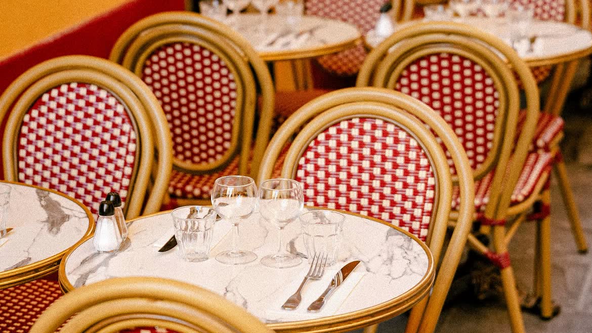 Les chaises de bistrot au cannage rouge et crème et les tables de marbre du Bouillon Saleya, devant le mur ocre